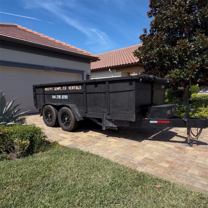 Mud Pit dump trailer parked on a paver driveway in front of a garage