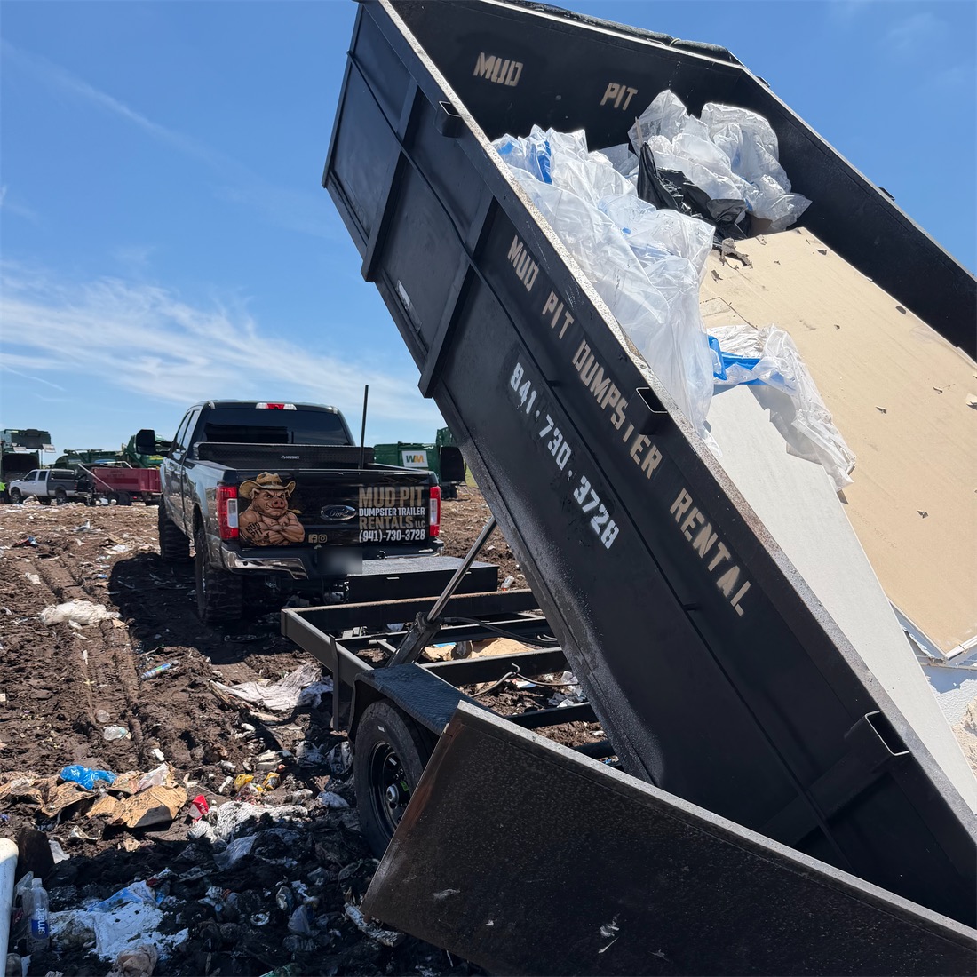 Mud Pit trailer tipped up and dumping at the landfill, the Mud Pit truck behind it